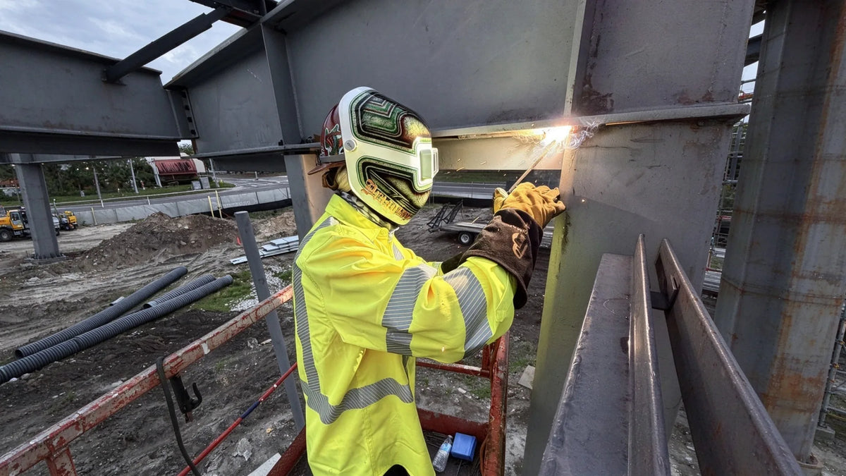 Worker welding in high-visibility arc-rated clothing
