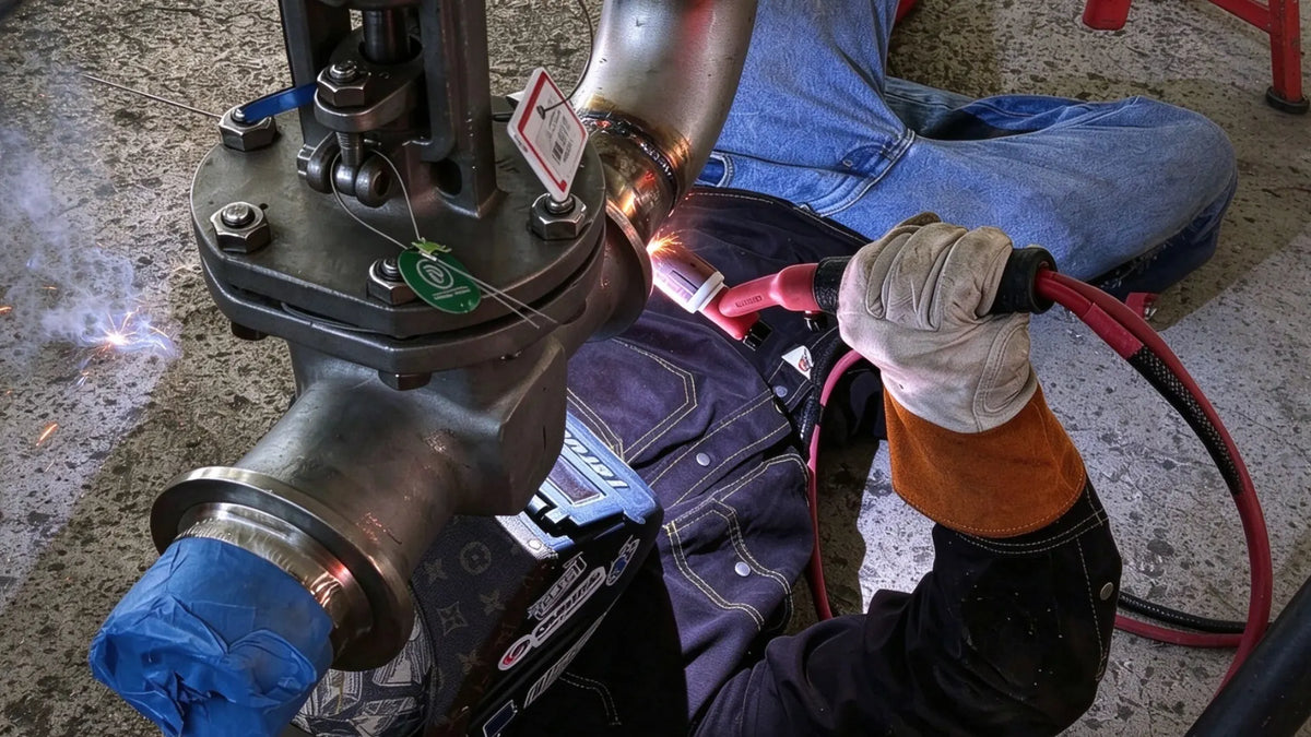 Worker repairing industrial pipe in FR clothing