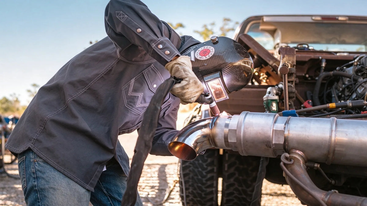 Worker welding exhaust pipe in FR workwear